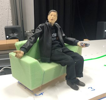 eine männliche Puppe sitzt auf einer grünen Couch