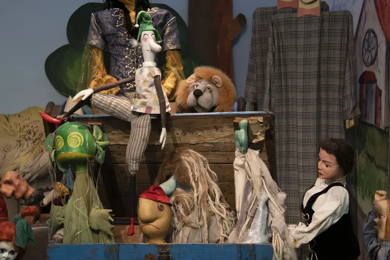 Verschiedene Puppen und ein Löwe, die in und auf einer Holzkiste sitzen